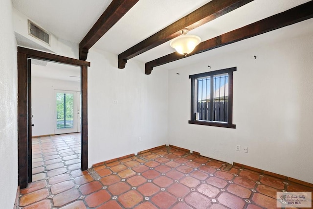 spare room featuring visible vents, beamed ceiling, and baseboards