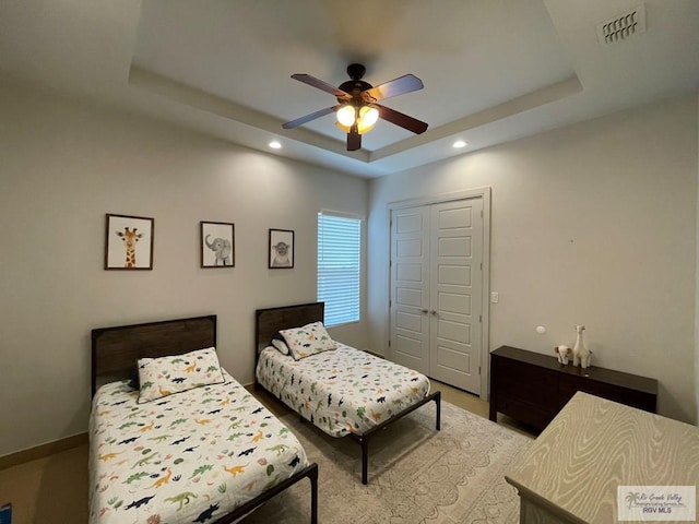 bedroom with a closet, ceiling fan, and a tray ceiling