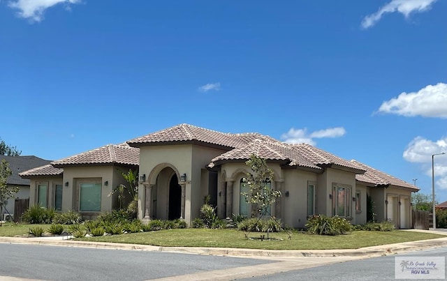 mediterranean / spanish-style house featuring a front yard and a garage