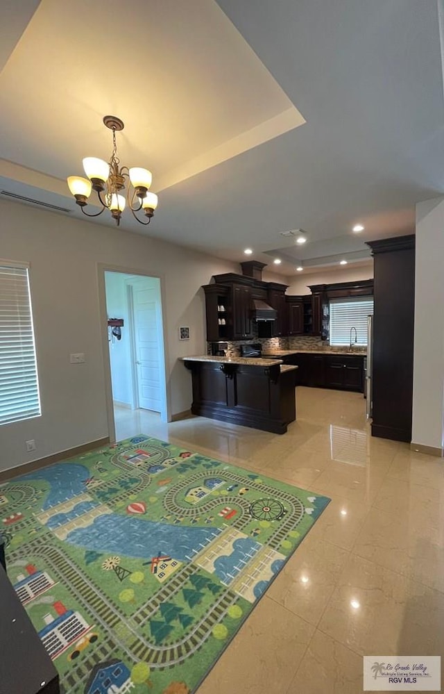 dining space with a chandelier, a raised ceiling, and sink