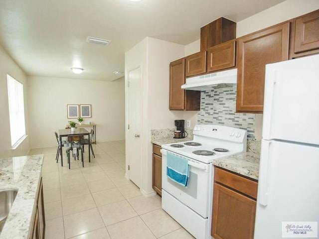 kitchen with light stone countertops, white appliances, light tile patterned floors, and tasteful backsplash