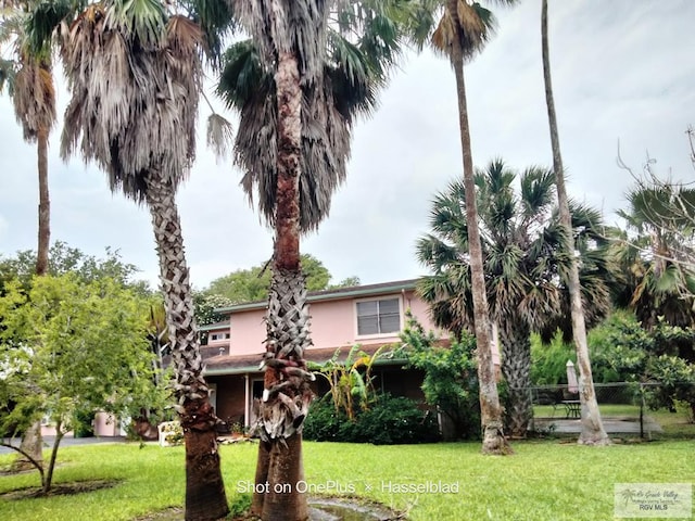 view of front of home featuring stucco siding, fence, and a front lawn
