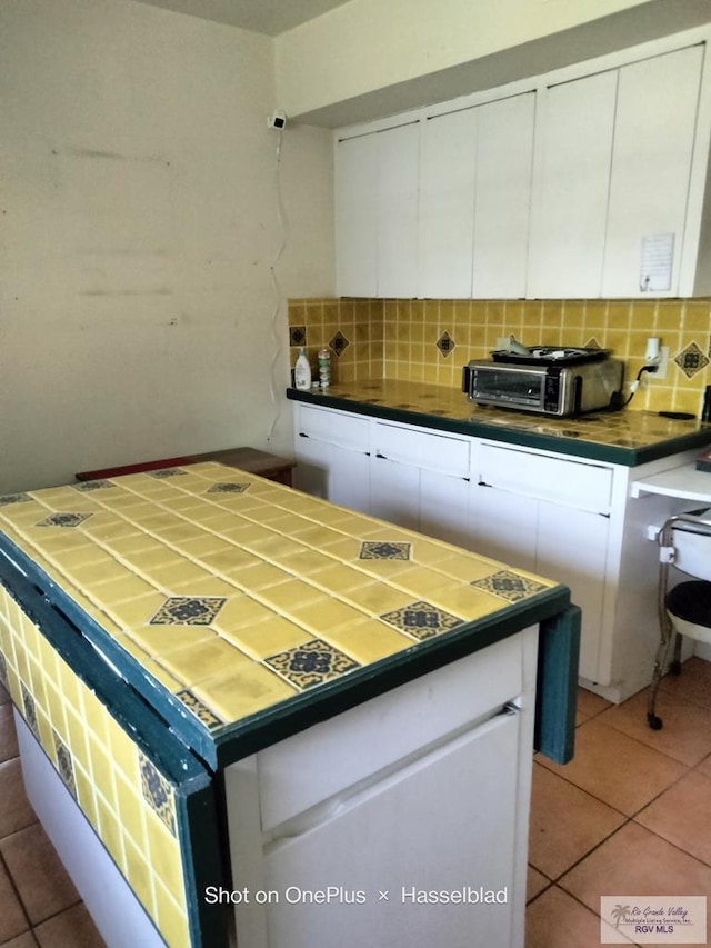 kitchen with a toaster, white cabinetry, tile patterned floors, and tasteful backsplash