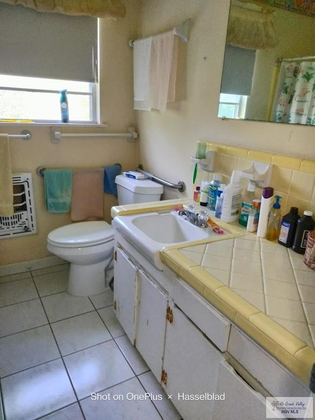 bathroom with toilet, vanity, heating unit, and tile patterned floors