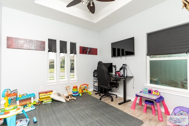 rec room with a tray ceiling, ceiling fan, and hardwood / wood-style flooring