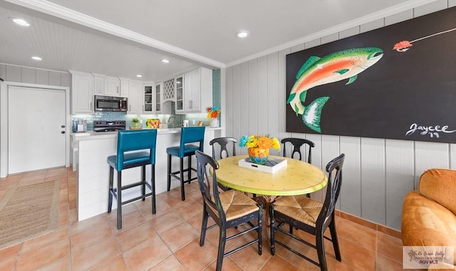 tiled dining room with wood walls and ornamental molding