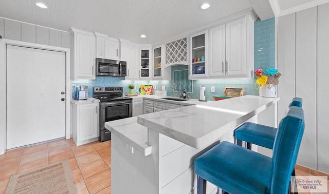 kitchen with kitchen peninsula, a breakfast bar, electric stove, light tile patterned floors, and white cabinetry