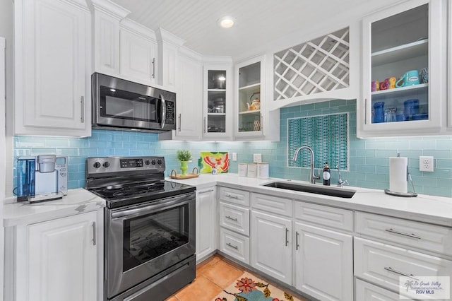 6201 Padre Blvd Unit 106, South Padre Island, TX 78597 - kitchen featuring stainless steel appliances, a sink, white cabinetry, light countertops, and decorative backsplash