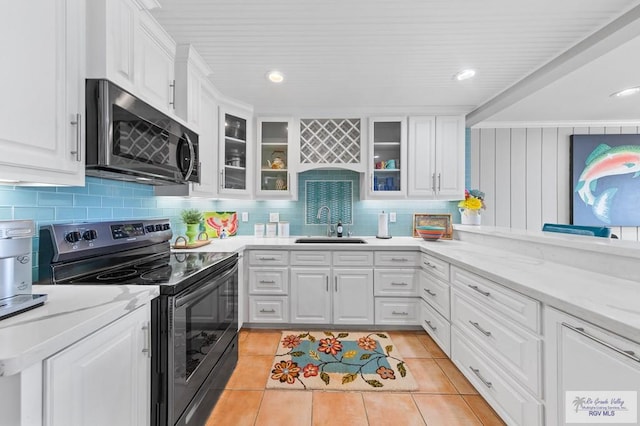 6201 Padre Blvd Unit 106, South Padre Island, TX 78597 - kitchen featuring black electric range oven, stainless steel microwave, a sink, light tile patterned floors, and white cabinetry