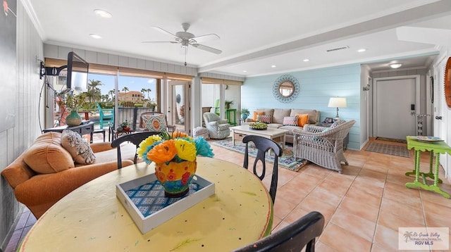 dining room featuring ceiling fan, wood walls, light tile patterned floors, and crown molding