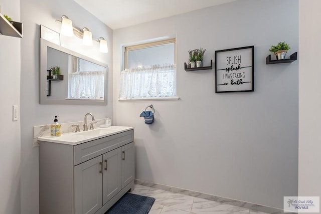 bathroom with marble finish floor, vanity, and baseboards