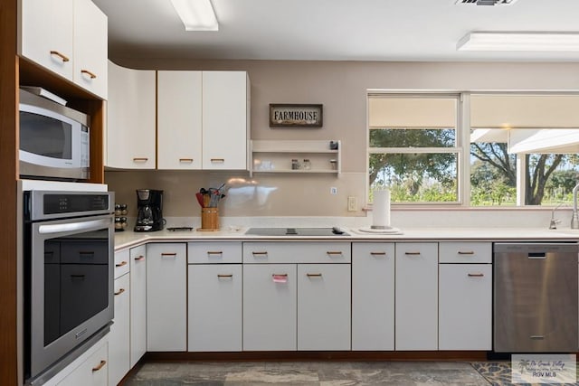 kitchen with stainless steel appliances, light countertops, visible vents, white cabinetry, and a sink