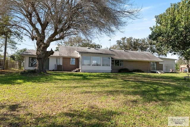 rear view of property with a yard and a sunroom