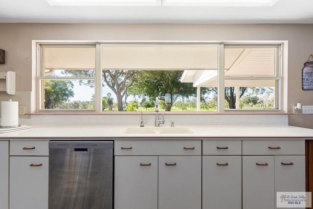 kitchen with dishwasher, light countertops, a sink, and a wealth of natural light