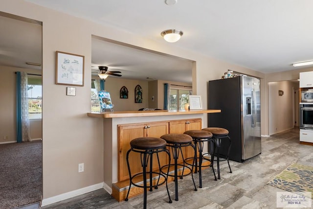 kitchen with a healthy amount of sunlight, baseboards, stainless steel appliances, and a kitchen breakfast bar