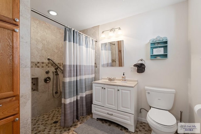 full bathroom featuring vanity, a tile shower, and toilet