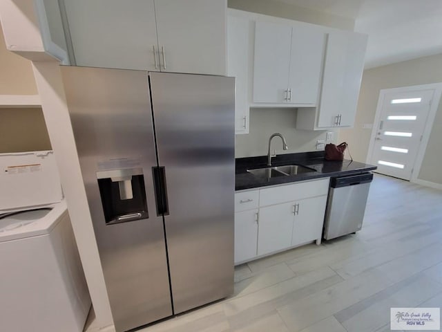 kitchen with sink, white cabinets, stainless steel appliances, and washer / dryer