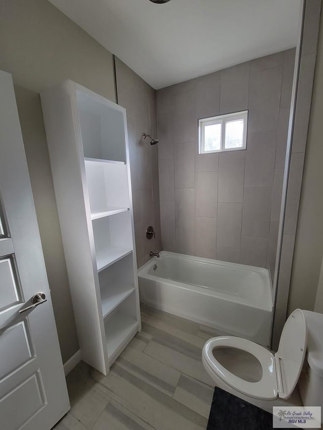 bathroom with tiled shower / bath combo and toilet