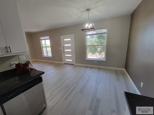 unfurnished dining area featuring light hardwood / wood-style flooring, a healthy amount of sunlight, and a notable chandelier