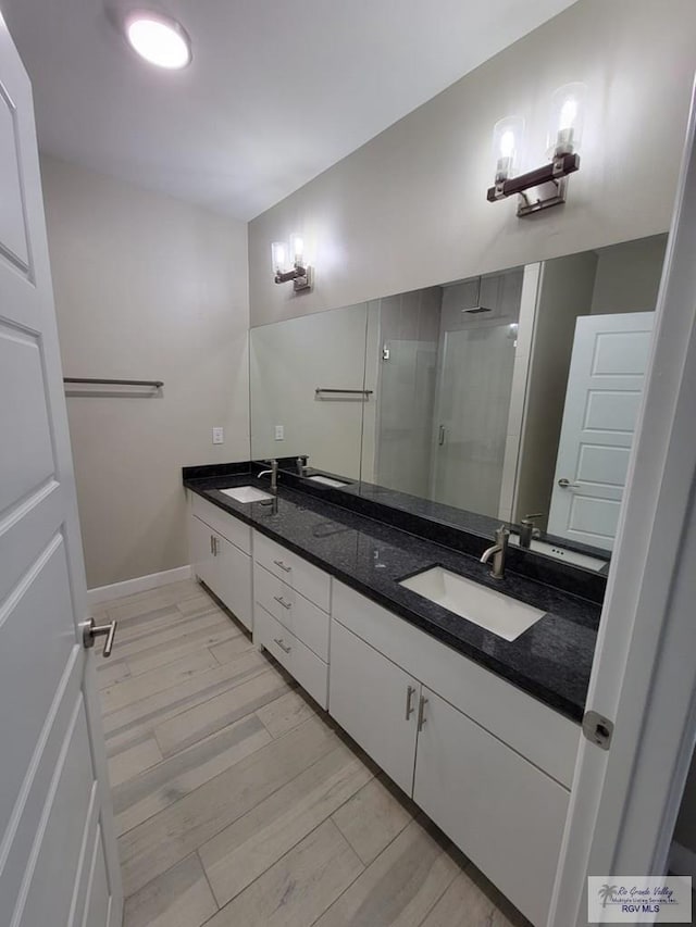 bathroom with wood-type flooring, vanity, and an enclosed shower