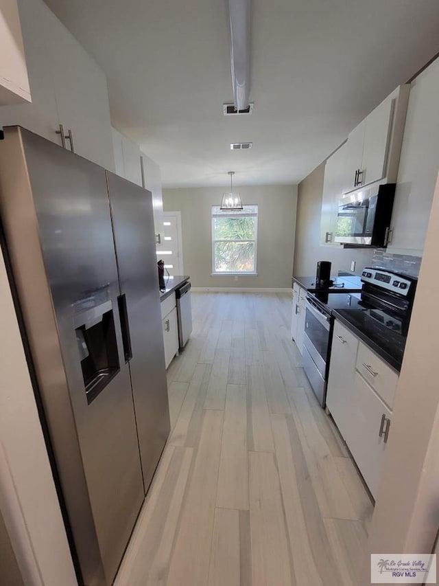 kitchen with hanging light fixtures, white cabinets, stainless steel appliances, and light wood-type flooring