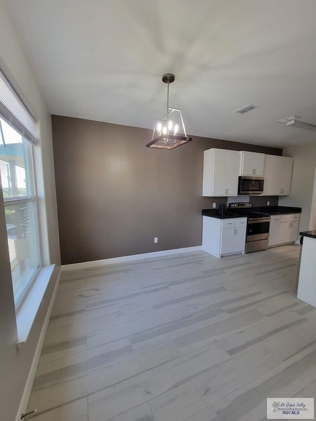 kitchen featuring appliances with stainless steel finishes, an inviting chandelier, white cabinets, light hardwood / wood-style floors, and hanging light fixtures