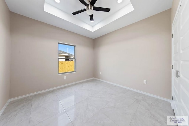 unfurnished room with a raised ceiling, baseboards, and ceiling fan