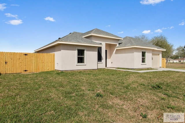 rear view of property with a lawn, fence, and stucco siding