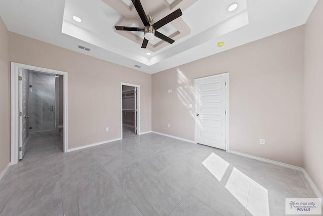 unfurnished bedroom featuring visible vents, a tray ceiling, recessed lighting, baseboards, and a spacious closet