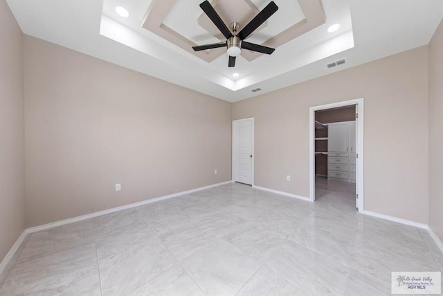 unfurnished bedroom featuring visible vents, a raised ceiling, recessed lighting, baseboards, and a spacious closet