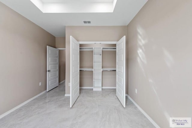 unfurnished bedroom with a closet, visible vents, marble finish floor, and baseboards