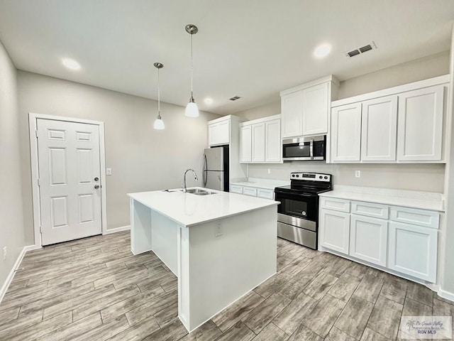1505 Shavano Dr, Edinburg, TX 78541 - kitchen featuring stainless steel appliances, light wood-style flooring, light countertops, a sink, and a kitchen island with sink