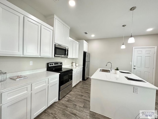 1505 Shavano Dr, Edinburg, TX 78541 - kitchen with appliances with stainless steel finishes, a sink, white cabinets, dark wood finished floors, and a center island with sink
