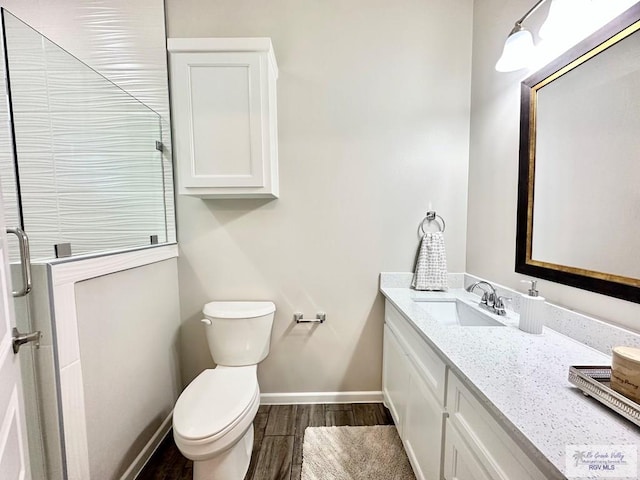 1505 Shavano Dr, Edinburg, TX 78541 - bathroom featuring wood finished floors, vanity, toilet, an enclosed shower, and baseboards