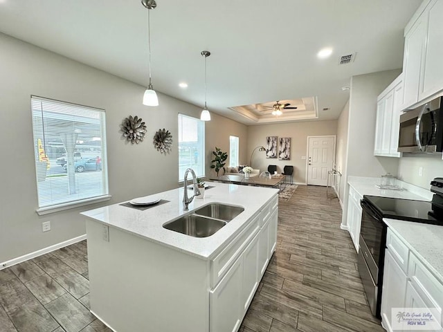 1505 Shavano Dr, Edinburg, TX 78541 - kitchen featuring black range with electric cooktop, a sink, stainless steel microwave, a tray ceiling, and open floor plan