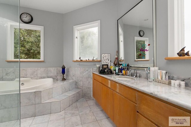 bathroom with vanity, a relaxing tiled tub, and tile patterned floors