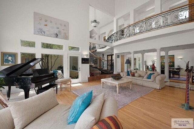 living room with ornate columns, a towering ceiling, and hardwood / wood-style flooring