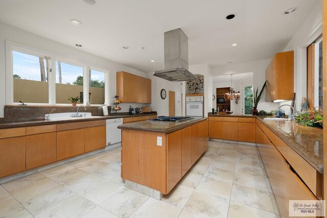 kitchen with dark stone counters, white appliances, island range hood, sink, and a kitchen island