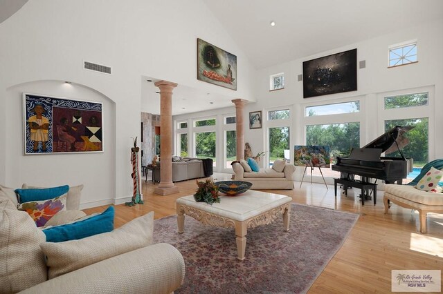 living room with high vaulted ceiling, ornate columns, and plenty of natural light