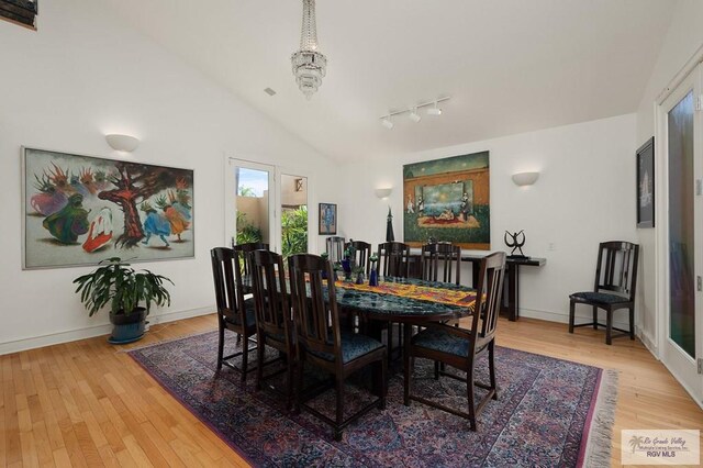 dining room with wood-type flooring, track lighting, and lofted ceiling