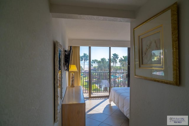 bedroom with light tile patterned flooring, beam ceiling, and access to outside