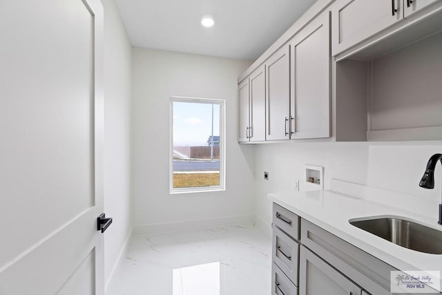 washroom featuring hookup for an electric dryer, marble finish floor, washer hookup, a sink, and baseboards