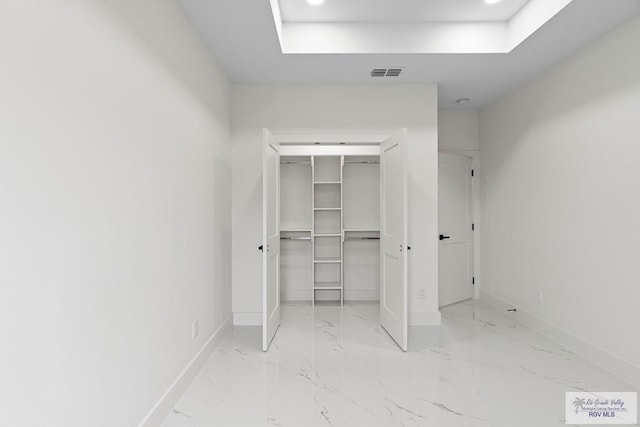 unfurnished bedroom featuring baseboards, visible vents, marble finish floor, and a tray ceiling