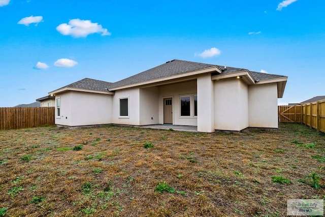 back of house featuring a lawn, stucco siding, a fenced backyard, and a patio area