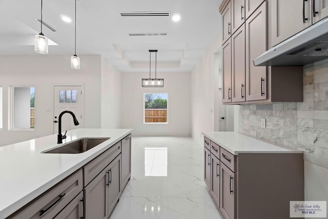 kitchen with a wealth of natural light, light countertops, under cabinet range hood, and a sink
