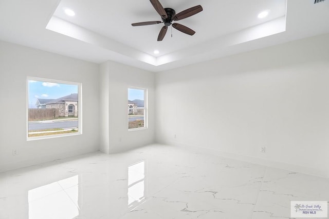 empty room featuring recessed lighting, ceiling fan, and a tray ceiling