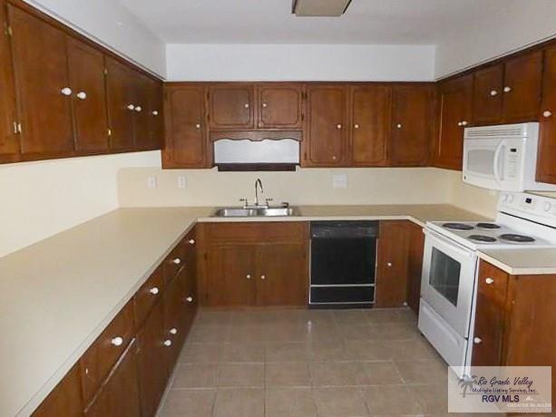 304 Hidden Valley Dr, Weslaco, TX 78596 - kitchen featuring white appliances, a sink, light tile patterned floors, light countertops, and brown cabinets