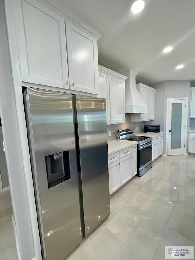 kitchen featuring white cabinets, custom range hood, and stainless steel appliances