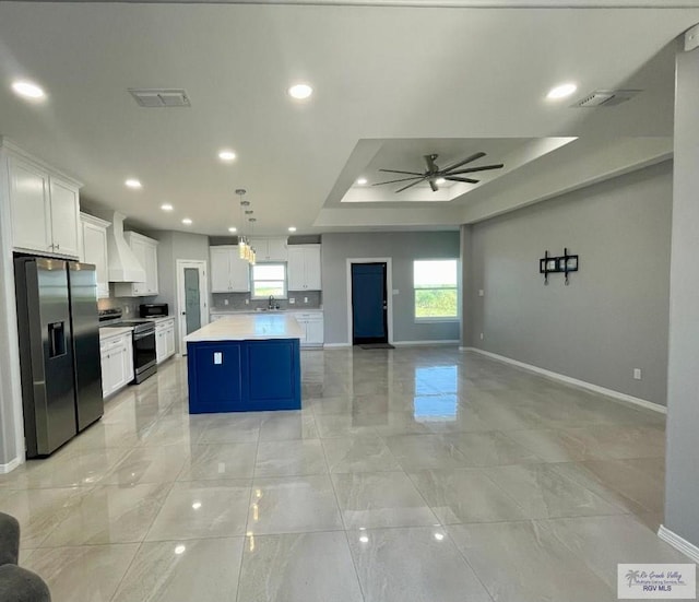 kitchen featuring white cabinetry, a center island, decorative light fixtures, appliances with stainless steel finishes, and custom exhaust hood