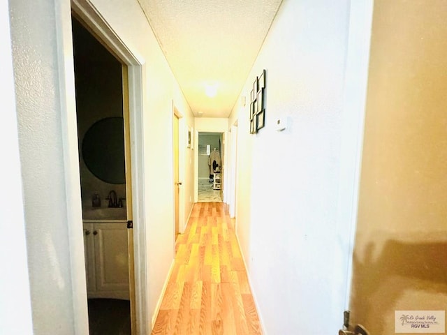 hallway with light hardwood / wood-style floors and sink